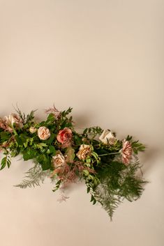 an arrangement of flowers and greenery on a white background