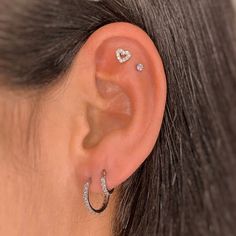 a woman wearing an ear piercing with two small diamonds on the inside of her ear