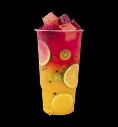 a cup filled with fruit and ice on top of a table next to a black background