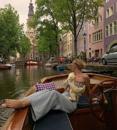 a woman sitting on the back of a boat in a canal