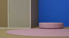 an empty room with a round rug and blue wall in the background, next to a pink chair