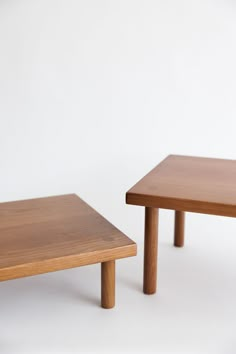 two wooden tables sitting next to each other on a white surface in front of a wall