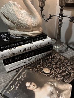 a stack of books sitting on top of a wooden table next to a candle holder