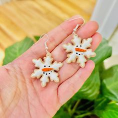 a person is holding two snowflakes in their hand and they are wearing earrings