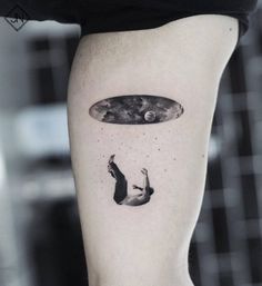 a woman's leg with a tattoo on it that has an image of a man falling from the sky