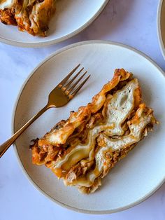 two plates with lasagna casserole on them, one has a fork