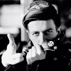 a black and white photo of a man wearing a hat making the middle finger sign