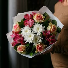 a woman holding a bouquet of flowers in her hands