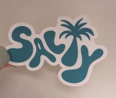 someone is holding up a sticker with the word sxs on it and palm trees