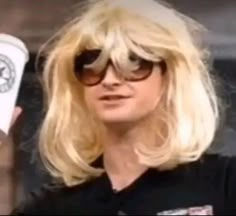 a woman with blonde hair and sunglasses holding up a starbucks cup