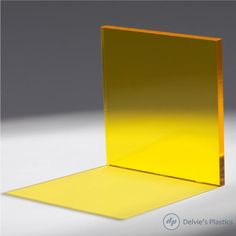 a yellow square shaped object on a white surface with light coming through the top and bottom