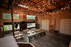 an empty room with tables and chairs in the middle is lit by lights hanging from the ceiling