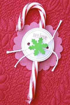 a candy cane with a green leaf on it is sitting on a red tablecloth