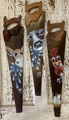 three old scissors are hanging on the wall with roosters and flowers painted on them