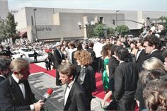 a group of people standing around each other on a red carpet with microphones in front of them