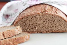 a loaf of bread sitting on top of a white plate next to a piece of bread