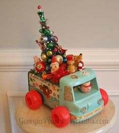 a toy truck filled with christmas ornaments on top of a white table next to a wall