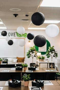 several black and white paper lanterns hanging from the ceiling in an office setting with tables and chairs