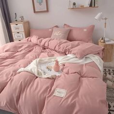 a bed with pink sheets and pillows in a bedroom