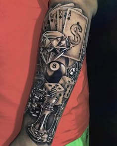 a man's arm with a black and grey tattoo on it, including playing cards