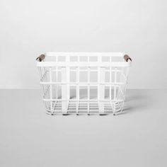 a white basket sitting on top of a gray floor next to a bird perched on it