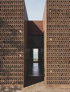 an entrance to a building made out of wooden lattices and stone blocks with a view of the ocean in the distance