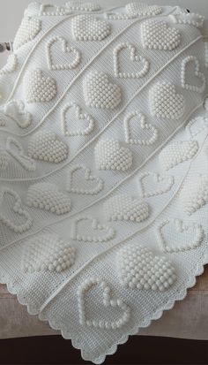 a white crocheted blanket with hearts on it