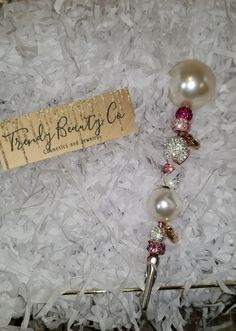 a necklace with pearls and swarongs on it in a box next to a tag