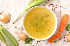 a bowl of soup with carrots, celery and onions on the side