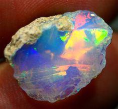 a close up of a person holding an opalite in their hand, with the light shining through it