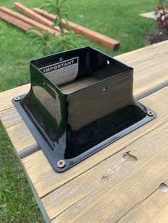 a black box sitting on top of a wooden table in the middle of a park