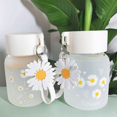 two bottles with flowers on them sitting next to a potted plant