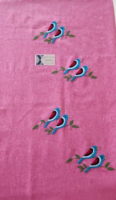 two blue birds sitting on top of a pink table cloth