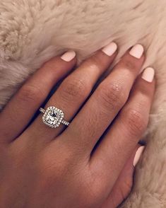 a woman's hand with a diamond ring on top of her finger, and a fur