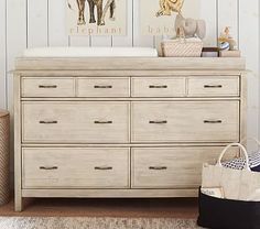 a baby's room with a dresser, crib and stuffed animals on the wall