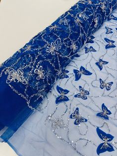 two blue dresses with butterfly appliques on them, one is draped over the other