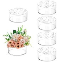 four clear vases with flowers in them on a white background and one is empty