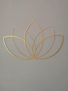 a gold metal wall decoration on a gray wall with a plant design in the middle