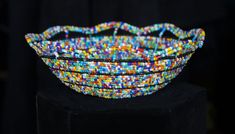 multicolored beaded bracelets stacked on top of each other in front of a black background