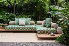 a green and white couch sitting on top of a wooden table in front of trees