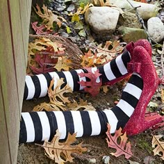 a woman's legs in striped socks and red boots with leaves around them on the ground