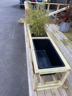 a wooden planter filled with plants on top of a wooden floor next to a parking lot