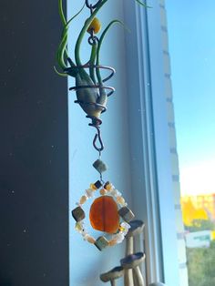 a wind chime hanging from the side of a window sill next to a potted plant