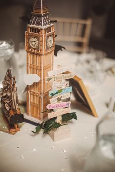 an image of a table setting with a clock tower in the middle and other decorations on it