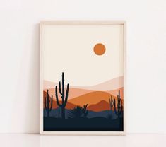 a desert scene with cacti and the sun in the sky, framed on a white wall