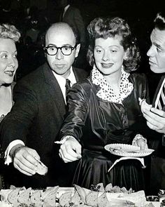 an old black and white photo of three people at a table with plates of food