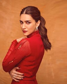 a woman in a red dress is posing for a photo with her hands on her chest