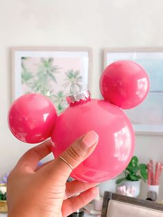 a hand holding a pink mickey mouse ornament