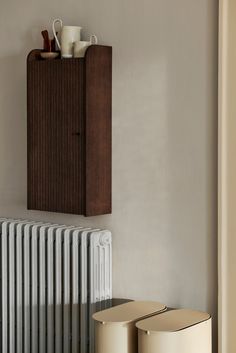 a radiator and two stools in front of a wall mounted shelf with coffee cups on it