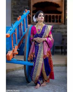 a woman in a blue and pink sari standing next to a wagon with wheels